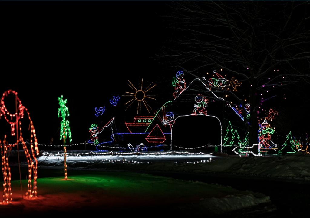 The landscape is covered in displays made out of christmas lights including many individual sculptures and a display of a house in the distance also made out of lights. 